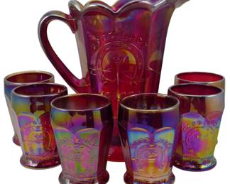 726 - Vtg Indiana Red Carnival Glass Pitcher Set (Description): Vintage Indiana red and yellow Good Luck  HOACGA 1974 carnival glass pitcher set. This  iridescent set features a scalloped rim  pitcher with applied handle and six matching  tumblers, each embossed with the Good Luck horseshoe motif and dated 1974. The glass  displays vibrant red carnival coloring with  rainbow iridescence. Pitcher measures 9  inches tall.