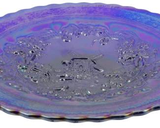 721 - Vtg Imperial Cobalt Windmill Carnival Glass (Description): Vintage Imperial cobalt blue carnival glass  dish featuring a detailed windmill scene in  the center. The plate displays a rich  iridescent finish with purple and blue hues,  and features a scalloped edge with ornate floral and scroll designs surrounding the  central windmill motif. Measures 9 inches in  diameter.
