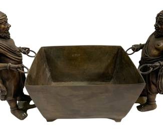1532 - Bronze Planter w/ Figural Handles 25"x15"x12" (Description): Bronze planter featuring two figural handles  depicting bearded male figures in classical  dress, each holding rope-like rings attached  to the rectangular vessel. The figures are  detailed with ornate headpieces and draped garments. The planter has a tapered  rectangular form with a rich patinated bronze  finish. Measures 25 inches by 15 inches by  12 inches.