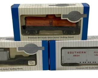 1618 - 3pc Lot Bachmann HO Scale Train Cars (Description): A lot of three Bachmann Premium HO Scale  Silver Series Rolling Stock train cars in  original boxes. The collection includes a  Southern Railway boxcar numbered 9824  featuring 'All-Door Loading' and 'Super Cushion Service' markings, a flatcar with  lumber load, and an orange tank car. All cars  are displayed in their original blue and  white striped packaging.