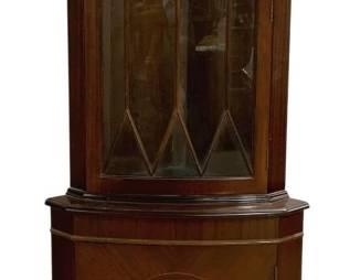 7755 - Petite English Narrow Corner Curio (Description): With attractive inlay details. The piece  features a bow-front design with an upper  glazed cabinet door featuring decorative  astragal glazing bars in a geometric diamond  pattern. The lower cabinet door displays a circular inlay medallion surrounded by  book-matched veneer. The cupboard has a  dentil molding detail at the crown and rests  on bracket feet. Measures 71 inches high by  26 inches wide by 15 inches deep.