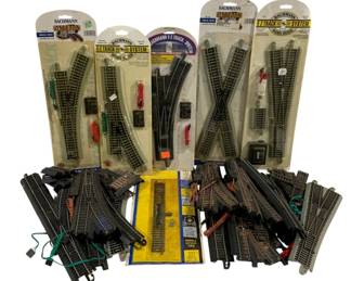 1073 - Bachmann E-Z Track HO Scale Train Track Lot (Description): Collection of Bachmann E-Z Track System HO  scale model railroad track pieces. The lot  includes five pieces in original retail  packaging featuring remote switches,  crossings, and straight sections with nickel silver rails. Additional loose track pieces  include curved sections, switches, and  straight track segments. Various accessories  and wiring components are included for layout  connectivity.
