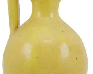 1001 - Vintage Yellow Pottery Rebecca Pitcher 9" (Description): Vintage yellow pottery Rebecca pitcher  featuring a distinctive tall looped handle  that rises above the rim and a trefoil-shaped  pouring spout. The pitcher has a bulbous  body tapering to a flared pedestal base, finished in a warm yellow glaze with subtle  amber accents on the handle. Measures 9  inches tall.