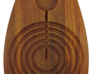972 - Dansk Denmark Teak Carving Board 20"x11" (Description): Dansk Denmark teak carving board featuring a  distinctive oval shape with carved concentric  circular grooves for collecting juices and a  well at the top for resting the carving  utensil. The board has a small hanging hole at the top. Measures 20 inches by 11 inches.