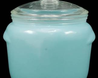 1220 - Small Turquoise Jar w/ Lid 4.5"x3.5" (Description): Small turquoise opaque glass jar with clear  glass lid. The jar features a rounded body  with tab handles on either side and a fitted  lid with a knob finial. Measures 4.5 inches  by 3.5 inches.