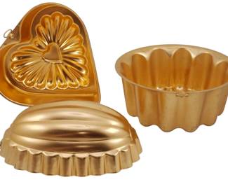 768 - 3 Copper Molds (Description): Collection of three copper molds in assorted  shapes. The set includes a decorative  heart-shaped mold with floral interior  design, a fluted round mold, and an oval  melon-shaped mold. Each features the classic copper finish typical of traditional  kitchenware.