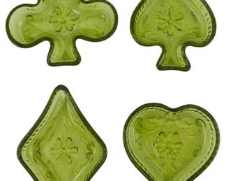 754 - 4 Indiana Tiara Green Glass Card Dishes (Description): A set of four Indiana Tiara green glass  dishes shaped as playing card suits. The  collection includes a club, spade, diamond,  and heart, each featuring an embossed floral  center design with decorative scrollwork and beaded border details. The pressedglass has a  rich avocado green coloring characteristic  of the Tiara line. These versatile dishes are  ideal for use as trinket holders, nut  dishes, or decorative accents.