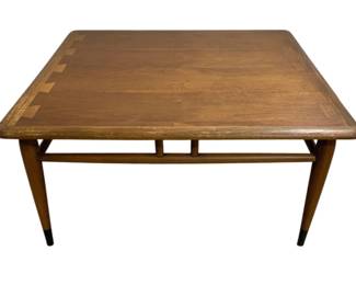 7616 - Lane Acclaim Walnut Square Coffee Table (Description): Mid-century modern coffee table in walnut  with a square top featuring softly rounded  edges. The table displays clean  Danish-inspired lines with tapered legs and a  lower stretcher framework connecting all four legs. The leg feet are capped in black.  Measures 14 inches high by 32 inches wide by  32 inches deep.