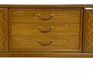7619 - Mid-Century United Furniture 1960s Credenza (Description): Mid-century modern cabinet console featuring  three center drawers with brass bail pulls  flanked by two doors with decorative lattice  overlay panels. The piece is constructed of  walnut with warm honey-toned finish and rests on a sculptural tapered leg base. Measures  32 inches high by 72 inches wide by 19 inches  deep.