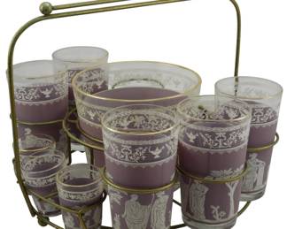 880 - Vtg Jeanette Lavender Hellenic Cocktail Set (Description): Vintage Jeanette lavender Hellenic cocktail  set featuring frosted purple glass decorated  with white classical Greek figures and  ornamental motifs. The set includes a gold  wire carrier caddy with handle, ice bucket, highball glasses, and shot glasses, all with  gold rim accents. The set is missing one  glass.