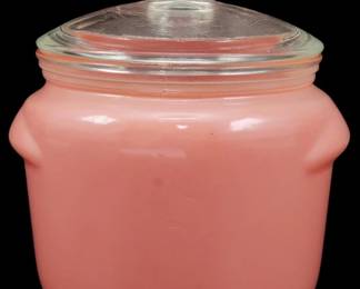 1165 - Vintage Pink Glass Jar w/ Lid 4.5"x3.5" (Description): Vintage pink glass jar with clear glass lid  featuring a rounded knob finial. The jar has  a charming opaque pink milk glass body with a  slightly curved silhouette and small tab  handles on either side. The clear glass lid fits snugly on the threaded rim. Measures  4.5" x 3.5".
