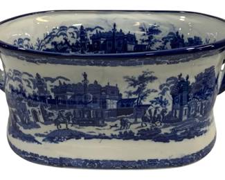 1540 - Blue & White Transferware Foot Bath Tub (Description): Blue and white transferware ceramic foot bath  tub featuring a scenic village design with  architectural elements, figures, and horses.  The oval vessel has applied handles on each  side and a cobalt blue rim. Measures 19" x 8.5" x 13".