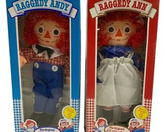 2017 - Playskool Raggedy Ann & Andy Dolls in Box 15" (Description): Pair of Playskool Raggedy Ann and Andy dolls  in their original boxes. These classic cloth  dolls feature the iconic red yarn hair,  triangle noses, and button eyes. Raggedy Andy  wears blue overalls with a red and white gingham shirt and bow tie, while Raggedy Ann  is dressed in a blue floral print dress with  white apron and red and white striped  stockings. Boxes are labeled "The Original  doll with a heart" and indicate the dolls are