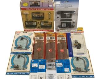 1654 - 15pc Lot HO Scale Train Accessories (Description): A collection of 15 pieces of HO scale train  accessories. The lot includes a Model Power  Highway & Street Set No. 329 featuring 6  hand-painted lighted pieces with gas station  signs and street lamps, a Railroad Accessories pack with crossing signals and  stop signs, Chooch HO scale loads, Model  Power brass handcrafted traffic lights, a  road signal, and various small hardware and  detail parts. Items remain in original