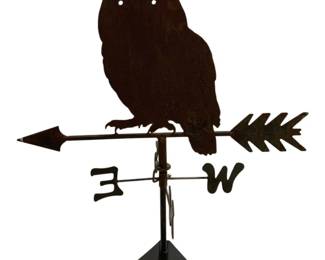 7706 - Owl Weather Vane 38"x27"x14" (Description): Owl weather vane crafted from metal with a  dark rust brown patina finish. Features a  silhouette owl perched atop a directional  arrow with E and W directional markers below.  The piece includes a mounting bracket base. Measures 38 inches by 27 inches by 14 inches.