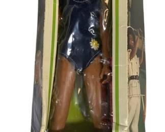 2011 - Kenner Dusty Fashion-Action Doll 11.5" (Description): Kenner Dusty "The Fashion-Action Doll" in  original box. This vintage 1974 doll features  blonde hair, blue eyes, and a poseable  athletic body wearing a navy blue swimsuit  with a daisy accent. The box shows some wear and creasing but the doll remains in good  condition. Contents include the Dusty doll,  swimsuit, and complete Fashion Action  booklet. Measures 11.5" tall.