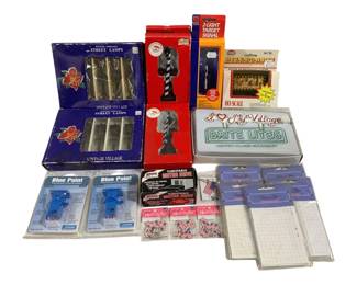 1655 - Lot of HO Scale Train Accessories & Parts (Description): A collection of HO scale train accessories  and parts including Vintage Village battery  operated street lamps, a 2-light target  signal, an HO scale billboard, I Love My  Village Brite Lites lighted village accessory, Blue Point turnout controllers,  Atlas turntable motor drive units, decorative  decals, and Frame-n-Trac display pieces.  Various items remain in original packaging.