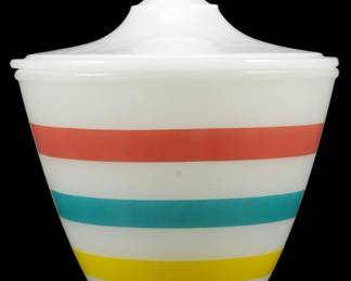 1025 - Fire King Colored Band Grease Jar w/ Lid (Description): Fire King milk glass grease jar with original  lid. Features a mid-century modern design  with horizontal bands in coral red, turquoise  blue, and yellow on white milk glass. The  jar has a tapered body with a fitted lid topped by a round finial knob. Measures 6  inches by 5.5 inches.