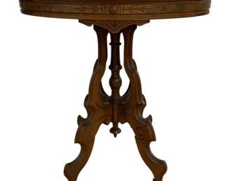 7713 - Victorian Oval Marble Top Table 30"x28"x22" (Description): Victorian marble top table featuring a white  marble surface with gray veining. The carved  walnut base displays elegant Eastlake-style  details with incised decorative patterns on  the apron and ornate scrolled legs. The base features a central turned finial and the legs  terminate in casters. Measures 30 inches  high by 28 inches wide by 22 inches deep.