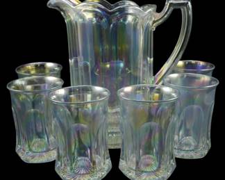 739 - Westmoreland Clear Iridescent Paneled Pitcher Set (Description): Vintage clear iridescent paneled glass  pitcher set featuring a ruffled rim pitcher  with applied handle and six matching  tumblers. The set displays beautiful rainbow  iridescence with elongated panel design and starburst pattern on the bases. Pitcher  measures 8 inches tall.