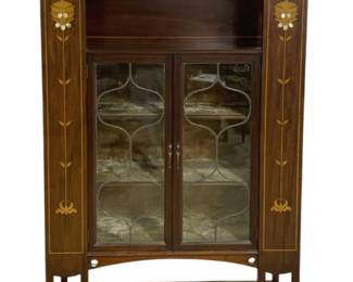7781 - Art Nouveau Inlaid Mahogany 2 Door Cabinet (Description): Art Nouveau style two-door cabinet in  mahogany with elegant floral marquetry inlay  along the vertical stiles. Features leaded  glass doors with decorative mullion patterns,  an open display shelf at the top with curved gallery and distinctive pierced heart-shaped  cutouts. The piece stands on tapered legs  with stretchers and displays characteristic  Art Nouveau stylized tulip and botanical  motifs in lighter contrasting wood inlay.
