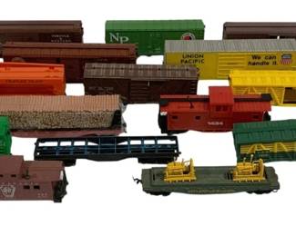 1609 - 16pc Lot HO Scale Train Cars (Description): A collection of 16 HO scale model train cars  featuring a variety of rolling stock. The lot  includes boxcars, gondolas, hoppers, stock  cars, flatcars, and cabooses in assorted  colors and railroad liveries including Union Pacific, Northern Pacific, and others.  Several cars feature detailed markings and  graphics. A diverse assortment suitable for  expanding an HO scale layout.