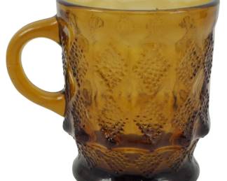 1067 - Anchor Hocking Fire King Amber Kimberly Mug (Description): Vintage Anchor Hocking Fire King mug in the  Kimberly pattern. Features a rich amber  coloring with a distinctive textured hobnail  and diamond design. The mug has a comfortable  C-shaped handle and footed base. Measures 4 inches tall.