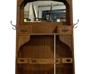 7758 - Vintage Art & Crafts Nuveau Hall Tree w/ Mirror (Description): Featuring Arts and Crafts styling with a  leaded glass panel at the top, a central  beveled mirror, and two small drawers with  decorative brass pulls. The piece includes  multiple double coat hooks on either side, a bead board back panel, and decorative  heart-shaped cutouts on the lower umbrella  stand section. Measures 73 inches tall by 36  inches wide by 12 inches deep.