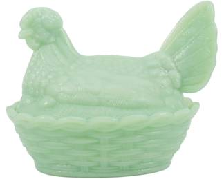 1047 - Jadeite Glass Hen on Nest Figure 5"x6"x4.5" (Description): Jadeite glass hen on nest figure in a soft  green opaque glass. The decorative covered  dish features a detailed hen with textured  feathers sitting atop a woven basket-style  base with scalloped edges. The lid lifts off to reveal a storage compartment. Measures 5"  x 6" x 4.5".