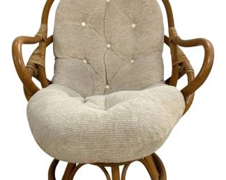 7642 - Vintage Rattan Bamboo Swivel Chair (Description): Vintage rattan bamboo swivel chair featuring  a curved bentwood frame with wrapped rattan  detailing on the arms. The chair includes a  plush tufted cushion in a neutral  oatmeal-colored woven fabric with button accents. The sculptural base allows for  smooth swivel rotation. Measures 42 inches  high by 31 inches wide by 30 inches deep.