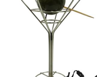942 - Post Modern Martini Lamp by David Krys (Description): Featuring a wire frame martini glass design  with a green olive-shaped globe and red  pimento accent. The sculptural lamp includes  a wooden cocktail pick element that passes  through the olive. Measures 15.5 inches tall. Used as is electric/electronic/mechanical  item. No guarantee all components, untested.