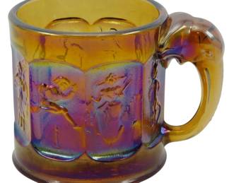 736 - Imperial Amber Nixon & Agnew Carnival Cup (Description): Vintage Imperial amber carnival glass cup  featuring Nixon and Agnew political motif.  The mug displays an iridescent finish with  purple and gold tones characteristic of  carnival glass. The piece features an elephant-shaped handle, a nod to the  Republican party symbol, and relief panels  depicting scenes around the body of the cup.