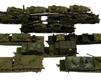 1576 - 9pc Lot Army Train Cars HO Scale (Description): A collection of nine HO scale army train cars  featuring military vehicles and equipment.  The lot includes flatbed rail cars loaded  with various military hardware including  tanks, artillery pieces, trucks, and armored vehicles. The pieces are finished in olive  drab and camouflage paint schemes typical of  U.S. Army equipment, with some vehicles  displaying military star insignia and unit  markings.