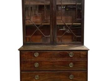 7754 - 2 Part English Mahogany Bookcase (Description): Two-piece mahogany secretary bookcase  featuring a glazed upper cabinet with  geometric astragal muntins and two glass  doors, surmounting a lower chest of drawers.  The chest consists of five graduated drawers with brass ring pulls, resting on bracket  feet. The upper section is crowned with a  dentil molding cornice. Georgian style  construction. Measures 89 inches tall by 38  inches wide by 23 inches deep.