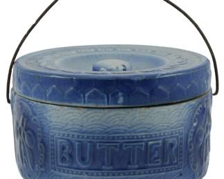 657 - Antique Blue & White Butter Crock 4"x7" (Description): Antique blue and white stoneware butter crock  with lid. The crock features the word  "BUTTER" embossed on the front and includes a  wire bail handle with wooden grip. Measures  4 inches tall by 7 inches in diameter.