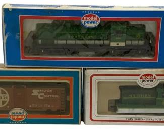 1617 - 3pc Lot Model Power HO Scale Train Cars (Description): Lot of three Model Power HO scale train cars  in original boxes. The collection includes a  Southern Railway green diesel locomotive, a  Santa Fe Shock Control boxcar in brown and  white, and a Southern Railway green extra duty locomotive with twin lights. All pieces  are housed in their original Model Power  packaging with display windows.