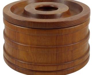 974 - Dansk Denmark Wooden Ice Bucket 5.5"x9" (Description): Dansk Denmark wooden ice bucket featuring a  cylindrical barrel-style design with  horizontal banded grooves and a fitted lid  with a recessed center handle. Crafted from  warm teak wood with visible grain throughout. Measures 5 1/2 inches tall by 9 inches in  diameter.