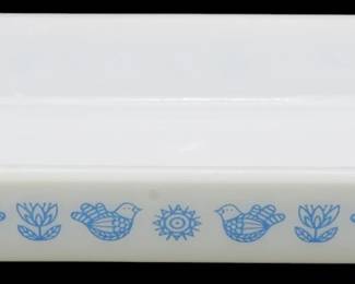 1212 - Glassbake Bird & Flower Baking Dish (Description): Glassbake rectangular baking dish featuring a  charming blue bird and flower pattern on  white milk glass. The folk art-inspired  design includes stylized birds, tulips, and a  central sunburst motif in a delicate blue print. Measures 2" x 12" x 7".