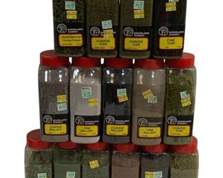 1694 - 15 Pc Woodland Scenics Turf & Ballast Lot (Description): A lot of 15 Woodland Scenics bottles for  model railroad and diorama landscaping. The  collection includes a variety of turf and  ballast materials in assorted colors and  textures, including coarse turf, fine turf, underbrush clump-foliage, bushes, coarse  ballast, fine ballast, and medium ballast.  Colors range from various shades of green to  earth tones including gray and brown. All  bottles feature the distinctive red Woodland