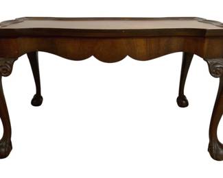 7666 - Chippendale Style Coffee Table 18"x32"x20" (Description): Chippendale style coffee table featuring a  shaped top with raised gallery edge and a  scalloped apron. The table rests on carved  cabriole legs with acanthus leaf detailing at  the knees, terminating in ball and claw feet. Crafted in a warm walnut finish.  Measures 18 inches high by 32 inches wide by  20 inches deep.