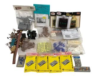 1699 - Lot HO Scale Train Accessories & Parts (Description): A collection of HO scale train items  including Atlas switch control boxes, Atlas  #215 Selector, Atlas #210 Twin control unit,  Grandt Line HO scale accessories, Bachmann  Plasticville building kits, and various loose parts and accessories. The lot contains  multiple packaged and loose components  suitable for model railroad layouts,  including figures, hardware, and scenic  elements from various manufacturers.