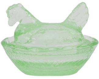 1054 - Green Glass Miniature Hen on Nest Figure (Description): Green glass miniature hen on nest figure.  This charming pressed glass piece features a  hen-shaped lid resting atop a basket-weave  patterned base. The translucent green glass  has a delicate, slightly frosted appearance with a diamond lattice design around the nest  portion. Measures 2 inches by 2.5 inches by  2 inches.