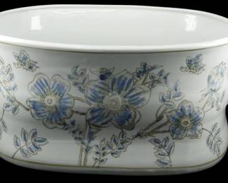 1037 - Blue Flower Decorated Large Planter (Description): Large white porcelain planter decorated with  blue floral motifs and delicate butterflies.  The oval-shaped vessel features graceful open  handles on either end and displays an  elegant Asian-inspired design with blue poppies or anemones, buds, and foliage  outlined in gold. The planter has a classic  footbath or cachepot form. Measures 8 inches  high by 18 inches long by 13 inches wide.
