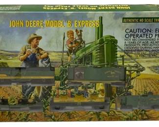 1700 - Athearn John Deere HO Scale Train Set (Description): Athearn John Deere Model 'B' Express  authentic HO scale train set. This officially  licensed John Deere product features a  complete train set including locomotive,  cars, and two die-cast Model B tractors. The set depicts classic John Deere green and  yellow livery with farm-themed graphics.  Original factory sealed box with agricultural  scene artwork.