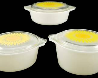 1215 - Pyrex Sunflower & White 3pc Casseroles Set (Description): Pyrex Sunflower and White three-piece  casserole set. This vintage collection  features white milk glass casserole dishes  with coordinating clear glass lids decorated  with cheerful yellow sunflower designs. The set includes three different sized  roundcasseroles, each with tab handles for  easy handling. A classic mid-century kitchen  collectible in the popular Sunflower pattern.