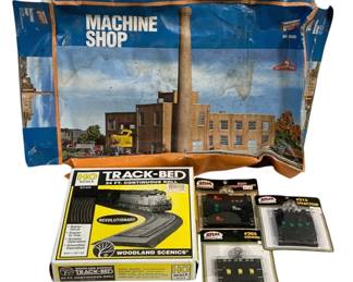 1701 - HO Scale Train Accessories Lot Machine Shop (Description): Lot of HO scale model train accessories  including a Machine Shop building kit by  Con-Cor, a Woodland Scenics Track-Bed 24 ft.  continuous roll, and three Atlas electrical  components including a #220 Controller, #205 Connector, and #215 Selector. Building kit  box shows wear. Accessories appear to be in  original packaging.