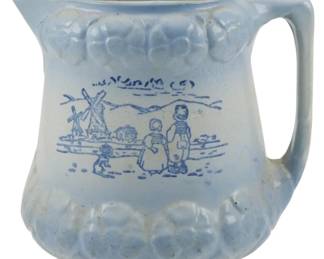 617 - Early 1900s McCoy Pottery Pitcher 7" (Description): Featuring a Dutch scene with windmill,  buildings, and figures in traditional dress.  The piece displays relief decoration along  the rim and base with a soft blue glaze.  Measures 7 inches.