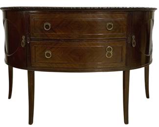 7773 - English Demilune Mahogany Buffet w/ Drawers (Description): Elegant demilune buffet crafted in mahogany  with beautiful book-matched veneer on the  drawer fronts. This piece features two center  drawers with brass ring pulls, flanked by  curved side cabinets with decorative oval inlay details. The top is finished with a  carved gallery edge, and the buffet stands on  four tapered legs. The overall design  reflects Regency or French-inspired styling.  Measures 38 inches high by 60 inches wide by