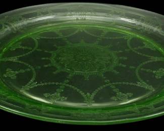 1244 - Vtg Anchor Hocking Cameo Uranium Glass Plate (Description): Vintage Anchor Hocking Cameo pattern uranium  depression glass plate in green. This round  serving plate features the distinctive Cameo  design with etched swags, scrollwork, and a  central medallion motif. The plate has decorative tab handles on opposite sides and  displays the characteristic green uranium  glass that glows under black light. Measures  10.5 inches in diameter.