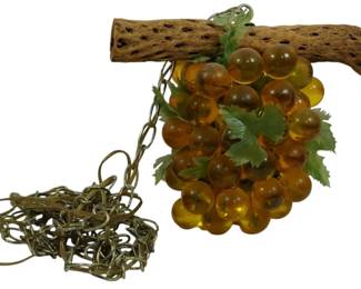 940 - Mid Century Amber Glass Grape Hanging Light (Description): Mid century hanging light featuring a cluster  of amber-colored glass grapes suspended from  a natural cholla wood branch. The decorative  fixture includes green plastic grape leaves  and comes with a hanging chain. A distinctive example of 1960s-1970s decorative lighting  popular during the era. Used as is electric/electronic/mechanical  item. No guarantee all components, untested.